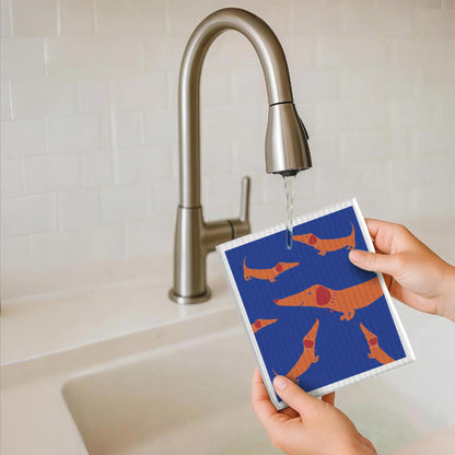 Schwammtuch mit Dackelmotiv in Blau und Orange, über der Spüle gehalten