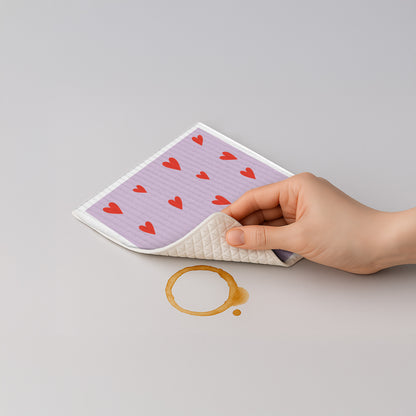Schwammtuch mit Herzmuster auf lilafarbenem Stoff, in der Hand