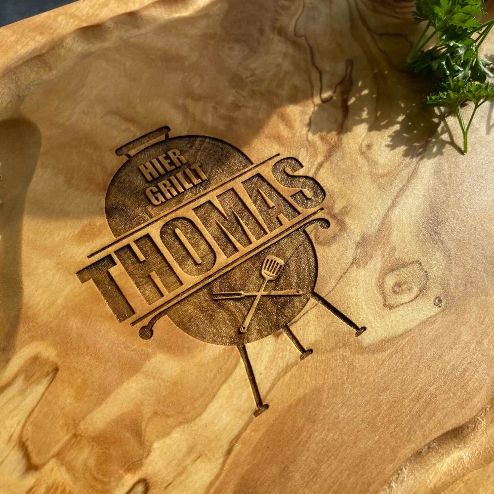 Gravur-Beispiel eines personalisierbaren Schneidebretts. Die Gravur zeigt einen Grill mit der Inschrift Hier grillt Thomas.